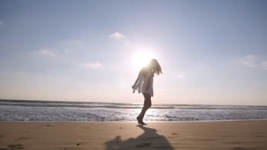 Okyanus Sahilde yürüyüş ve su püskürtme ayakları ile mutlu bir kadın. Genç güzel kız hayattan zevk ve deniz sahilinde eğleniyor. Yaz tatili. Arka plan manzara. Slowmotion