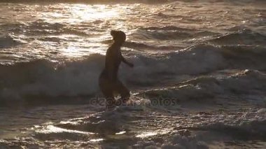 Genç kadın denizden Yüzme gün batımında sonra yürüyüş mayo. Güzel genç kız okyanus su tatil sırasında plaja adım. Yaz tatile dinlenmek. Ağır çekim