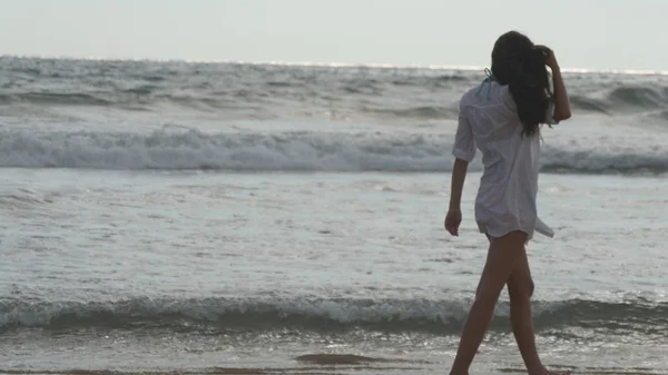 Ευτυχισμένη γυναίκα που περπατά στην παραλία κοντά στον ωκεανό. Όμορφη κοπέλα απολαμβάνοντας τη ζωή και τη διασκέδαση στο κύμα της θάλασσας. Ή καλοκαιρινές διακοπές. Τοπίο της φύσης στο φόντο — Φωτογραφία Αρχείου