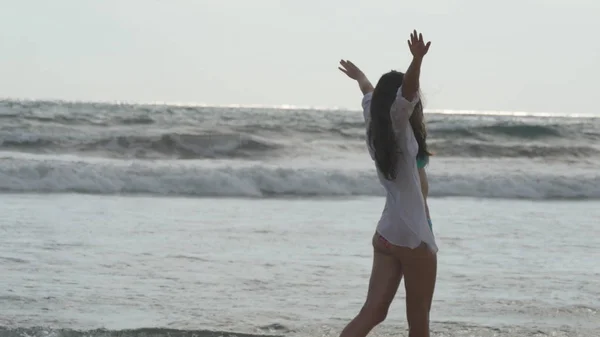 Donna felice che cammina e gioca sulla spiaggia vicino all'oceano. Giovane bella ragazza godendo la vita e divertirsi sulla riva del mare. Vacanze estive o vacanze. Paesaggio naturale sullo sfondo — Foto Stock