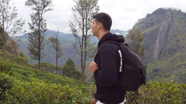 年轻男子旅游带背包行走在山径与背景在美丽的自然景观。男性的徒步旅行者，在热带山的道路。健康积极的生活方式。旅游概念 — 图库照片