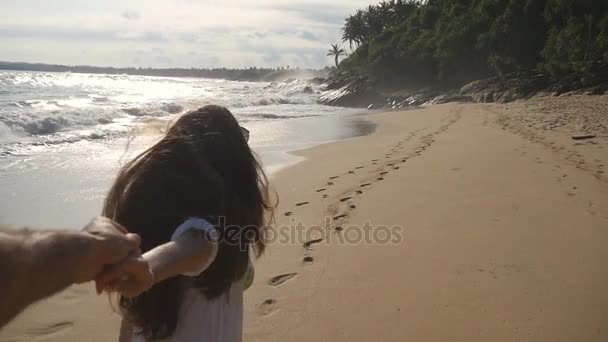 Siga-me tiro da jovem mulher puxar o namorado na costa do mar. Menina segurando a mão masculina e correndo na praia tropical exótica para o oceano. Férias de verão ou férias. Ponto de vista. POV Movimento lento — Vídeo de Stock