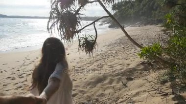 Erkek elini tutarak ve tropikal egzotik kumsalda okyanusa çalışan kız. Genç kadın çekin sevgilisi deniz kıyısında vurdu beni takip edin. Yaz tatili ya da tatil. Bir bakış açısı. POV ağır çekim