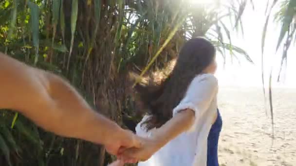 Menina segurando a mão masculina e correndo na praia tropical exótica para o oceano. Siga-me tiro da jovem mulher puxar o namorado na costa do mar. Férias de verão ou férias. Ponto de vista. POV Movimento lento — Vídeo de Stock