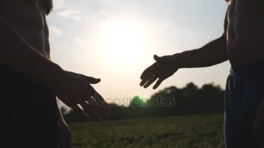 Dost karşılıklı iki tanınmaz kas beyaz adamın güneş, arka plan ile. Erkek silah açık sallayarak. İki güçlü adam dışında toplantı. Takım çalışması ve dostluk. Yavaş hareket kapatmak