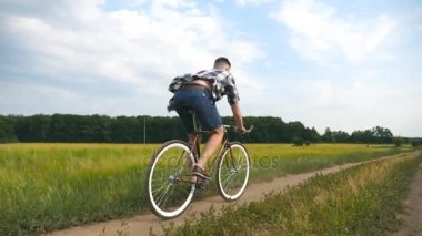 Kırsal alanda bisiklet süren genç bir adam var. Sportif adam şehir dışında bisiklet sürüyor. Erkek bisikletçi kırsalda bisiklet sürüyor. Sağlıklı aktif yaşam tarzı Yavaş çekim