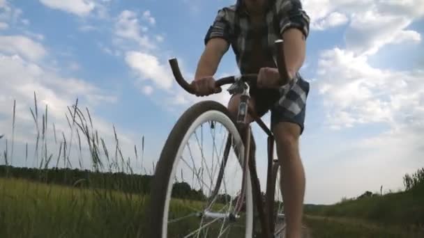 若い男が畑の上の田舎道でヴィンテージ自転車に乗っている。田舎のトレイルアウトドアに沿ってスポーティ男サイクリング。田舎で自転車に乗る男性サイクリスト。健康的なアクティブなライフスタイルスローモーション — ストック動画