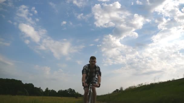 若い男が畑の上の田舎道でヴィンテージ自転車に乗っている。田舎のトレイルアウトドアに沿ってスポーティ男サイクリング。田舎で自転車に乗る男性サイクリスト。健康的なアクティブなライフスタイルスローモーション — ストック動画