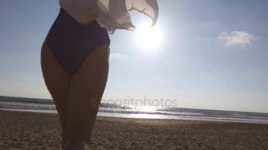 Okyanusa günbatımı ve yükseltilmiş elinde plajda çalışan genç kadın. Kumlu sahilde denize gidiyor ve tatil sırasında özgürlük zevk güzel genç kız. Yaz tatile dinlenmek. Arka arkadan görünüm