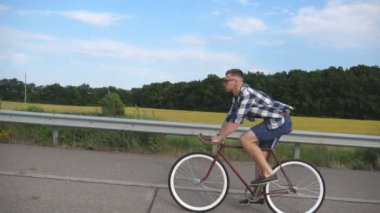 Ülkede yol Vintage Bisiklet sürme yakışıklı delikanlı. Sportif adam pistte Bisiklete binme. Erkek bisikletçi sabit sürme karayolu Bisiklet dişli. Sağlıklı aktif yaşam tarzı ağır çekim