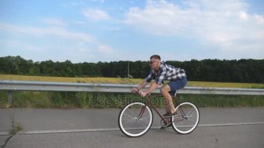 Ülkede yol Vintage Bisiklet sürme yakışıklı delikanlı. Sportif adam pistte Bisiklete binme. Erkek bisikletçi sabit sürme karayolu Bisiklet dişli. Sağlıklı aktif yaşam tarzı ağır çekim