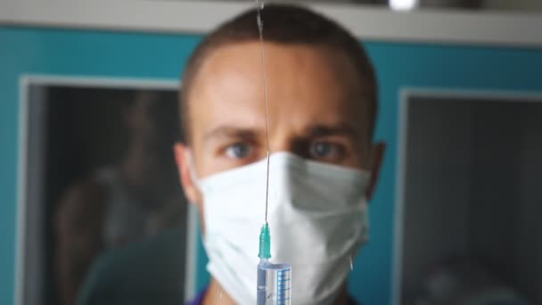 Retrato do jovem médico caucasiano na máscara derramando um líquido de uma seringa. Trabalhador médico a preparar a seringa para injecção. Medicina conceito de cuidados de saúde. Lento movimento Fechar — Vídeo de Stock