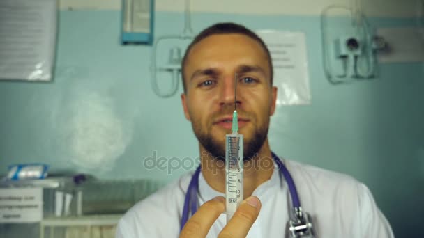 Retrato de un joven doctor caucásico vertiendo un líquido de una jeringa y sonriendo. Trabajador médico que prepara la jeringa para inyección. Medicina concepto de cuidado de la salud. Cámara lenta Primer plano — Vídeos de Stock