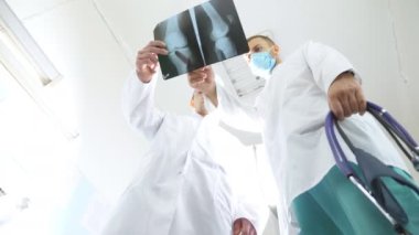 İki beyaz doktor MRI resim ve bu konuda tartışmaya görüntüleyin. Hastanede tıbbi işçi x-ışını baskılar inceleyin. Erkek sağlık görevlilerinin birbirleri ile x ışını Image'da bakarken bakın. Düşük görüş açısı