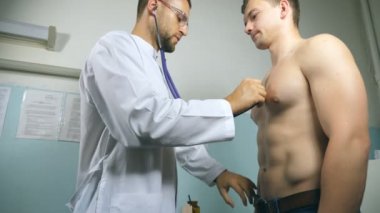 Doktor muayene genç erkek hasta stetoskop ile. Göğüs Hastanesi ofisinde bir adam kontrol doktor. Tıbbi işçi dinleme kalp atışı atletik adam. Yakın çekim