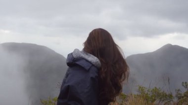 Güzel Kanyon kenarında oturan ve doğa arayan kadın seyahat. Dağlarda manzarayı yağmurluk genç kadın turist. Yan görünümü kapatın