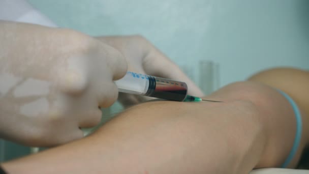 医師の手は患者の静脈から注射器を抽出します。テスト用の血液サンプルを取る。血を取って医者の腕。クローズ アップ — ストック動画