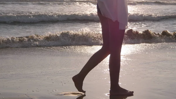 Donna che cammina sulla spiaggia sabbiosa vicino all'oceano. Giovane bella ragazza godendo la vita e andare sulla riva del mare. Vacanze estive o vacanze. Paesaggio marino sullo sfondo. Vista posteriore posteriore — Foto Stock