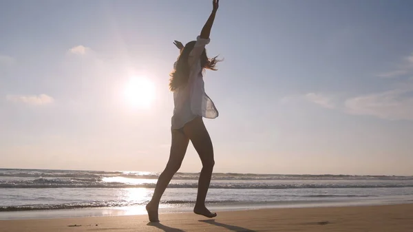 Lycklig kvinna springer och snurrar på stranden nära havet. Ung vacker flicka njuter av livet och ha roligt på havet. Sommar semester eller semester. Natur landskap i bakgrunden — Stockfoto