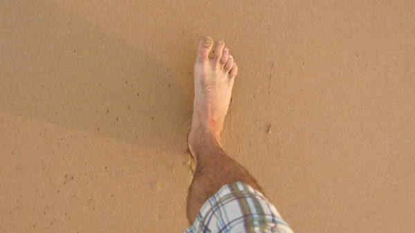 Точка зрения молодого спортсмена, бегущего по золотому песку на морском пляже. Мужские ноги спортсмена бегают возле океана. Голая нога парня, идущего по песчаному берегу. Здоровый активный образ жизни. Закрыть POV — стоковое фото