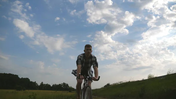 Joven montando bicicleta vintage en la carretera rural sobre el campo. Deportivo ciclismo chico a lo largo del país sendero al aire libre. Bicicleta ciclista masculino en el campo. Vida activa saludable Movimiento lento — Foto de Stock