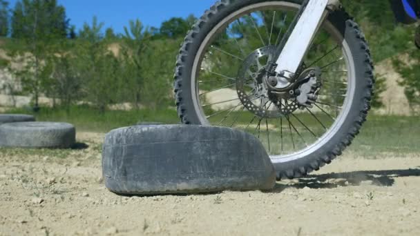 Motocross rider supera la barrera del neumático viejo. Las ruedas de enduro superan el obstáculo. Primer plano: cámara lenta — Vídeos de Stock