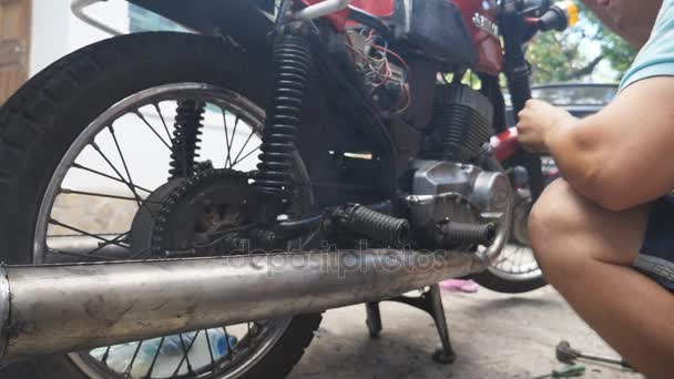 Caucásico mecánico de automóviles repara su vieja motocicleta al aire libre. Cámara lenta Primer plano — Vídeos de Stock