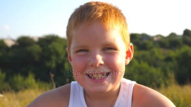 Çilli mutlu kızıl saçlı çocuğun portresi açık havada gülüyor. Sevimli yakışıklı bebek neşeli bir gülümsemeyle kameraya bakıyor. Yüzünde mutlu bir ifade olan erkek çocuğun duygularını kapat. Yavaş çekim