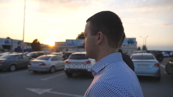 Two young businessmen walking in auto parking at sunset time. Business men commuting to work together. Confident guys being on his way to office. Colleagues going outdoor. Slow motion Close up — Stock Video