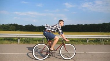 Ülkede yol Vintage Bisiklet sürme yakışıklı delikanlı. Sportif adam pistte Bisiklete binme. Erkek bisikletçi sabit sürme karayolu Bisiklet dişli. Sağlıklı aktif yaşam tarzı ağır çekim