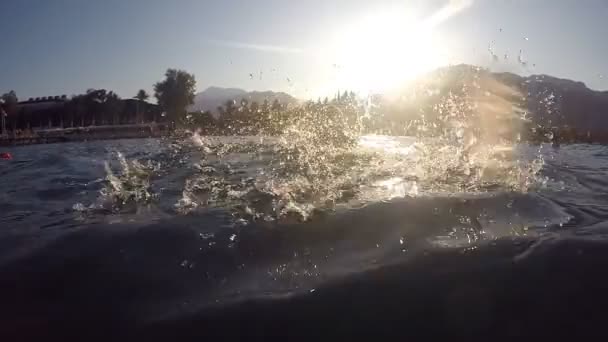 Chica joven en el mar durante las vacaciones de verano. Mujer sonriente nadando y rocía agua en la cámara. Concepto de vacaciones. Movimiento lento — Vídeo de stock