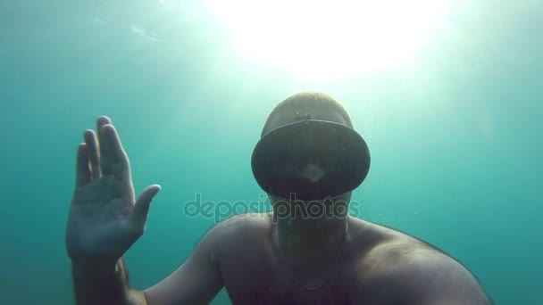 Man onderwater in masker om te zwemmen. Guy duiken en salutes. Camera is in de hand, zijn zelfportret. Onderwater beelden. Slow motion — Stockvideo