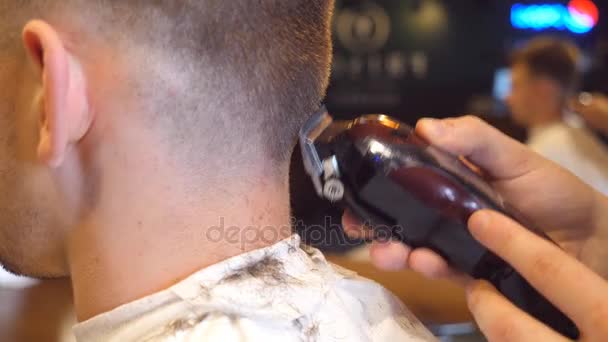 Ο άνθρωπος κουρέας κοπής μαλλιά στο λαιμό του αρσενικό πελάτη με clipper στο κουρείο. Διαδικασία κομμωτικής. Αργή κίνηση, κοντινό πλάνο — Αρχείο Βίντεο