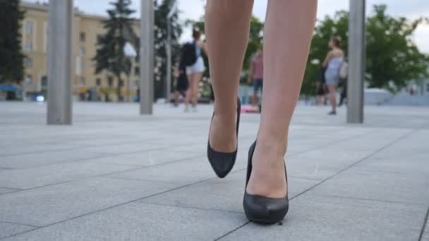 Fötter av ung affärskvinna i högklackade skor går i staden. Kvinnliga ben i höga klackar skor promenader i urban street. Flicka kliva för att arbeta. Slow motion Stäng upp Front vy — Stockvideo