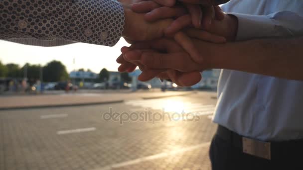 Arms of three business men stacked together in unity and teamwork. Hands of businessman team getting together in the center of a circle and then raised. Sun flare at background. Slow motion Close up