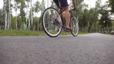 Dışarıda klasik bir bisiklete binen genç yakışıklı adam. Parkta bisiklete binen sporcu çocuk. Sağlıklı aktif yaşam tarzı. Yavaşça kapat.