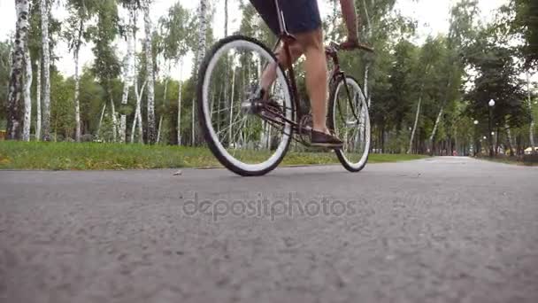 Jovem homem bonito montando uma bicicleta vintage ao ar livre. Um tipo desportivo a andar de bicicleta no parque. Estilo de vida ativo saudável. Fechar câmera lenta — Vídeo de Stock