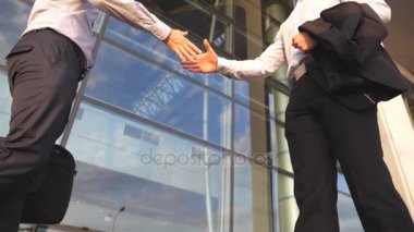 İki işadamı ofis binasının yakınında buluşup birbirlerini selamlıyorlar. Şehir ortamında iş tokalaşması. Erkek kollarını dışarıda sallıyor. Meslektaşlar el sıkışır. Yavaşça kapat.