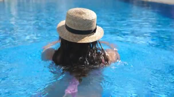 Parte posterior de la joven chica irreconocible en el sombrero nadando en la piscina. Mujer relajándose en el lavabo. Concepto de vacaciones. Vista trasera Cerrar Cámara lenta — Vídeo de stock