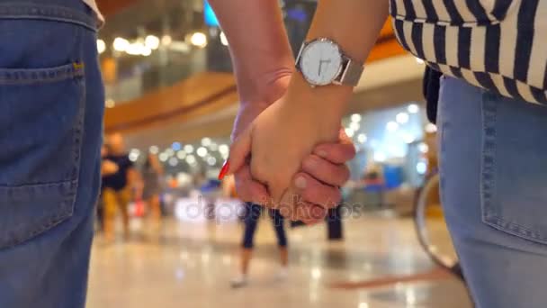 Young couple holding hands of each other and walking at terminal of airport. Man and woman taking arms and stepping during trip. Symbol of love and devotion. Close up Slow motion — Stock Video