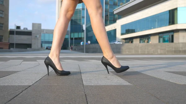 Γυναικεία πόδια με ψηλά τακούνια παπούτσια που περπατούν στον αστικό δρόμο. Πόδια νεαρής επιχειρηματία με ψηλοτάκουνα παπούτσια να πηγαίνουν στην πόλη. Κορίτσι που πηγαίνει στη δουλειά. Αργή κίνηση Κλείσιμο — Φωτογραφία Αρχείου