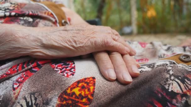 Runzelige Hände der Seniorin. Arm der alten Großmutter, die draußen sitzt. Nahaufnahme Seitenansicht Zeitlupe — Stockvideo