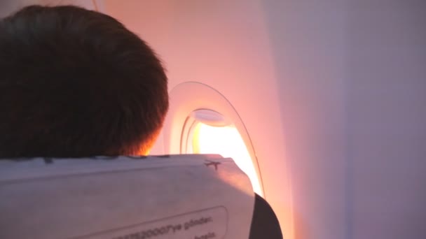 Un uomo irriconoscibile che guarda al finestrino dell'aereo durante il volo. Passeggero in aereo. Concetto turistico. Vista posteriore posteriore — Video Stock