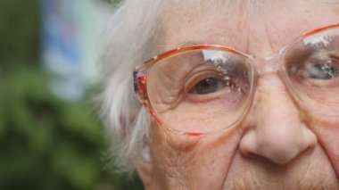 Dolly eski kadın gözlük açık vurmuş. Gözleri yaşlı bir Bayan ile onları çevresindeki kırışıklıklar. Büyükanne portresi kapatın. Ağır çekim