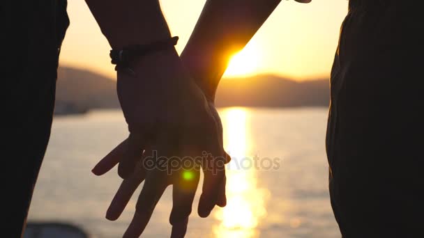 Силует чоловічих і жіночих рук тримає один одного на заході сонця на морському тлі. Молода пара приєднується до зброї на відкритому повітрі. Концепція любові та щастя. Крупним планом Задній перегляд Повільний рух — стокове відео
