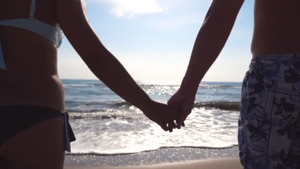 Young couple in love standing at sea shore and enjoying beautiful view. Male and female arms comforting and stroking each other on the beach. Summer vacation or holiday. Close up Rear back view — Stock Video