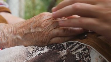 Yaşlı bir rahatlatıcı genç erkek silah eski kadın elleri açık eşleyin. Torun ve büyükanne dışarıda birlikte vakit. Bakım ve kavram sevgi dolu. Yan görünümü ağır çekim kapatın