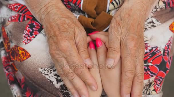 Velha mulher acariciando jovens mãos femininas. A neta e a avó passam tempo juntas. Conceito carinhoso e amoroso. Fechar para cima Visão superior Lento movimento — Vídeo de Stock