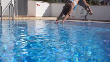 Genç güzel kadın güneşli günde Havzası suya atlama. Esmer kız havuzda ve güneşli günde rahatlatıcı. Yaz tatil veya tatil kavramı. Yavaş hareket kapatmak