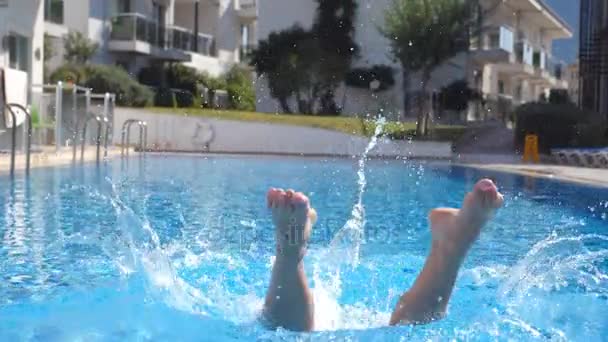 Jonge mooie vrouw springt in het bassin en komt dan onder water vandaan. Brunette meisje zwemmen in het zwembad en ontspannen op zonnige dag. Zomervakantie of vakantie concept. Sluiten Slow motion — Stockvideo